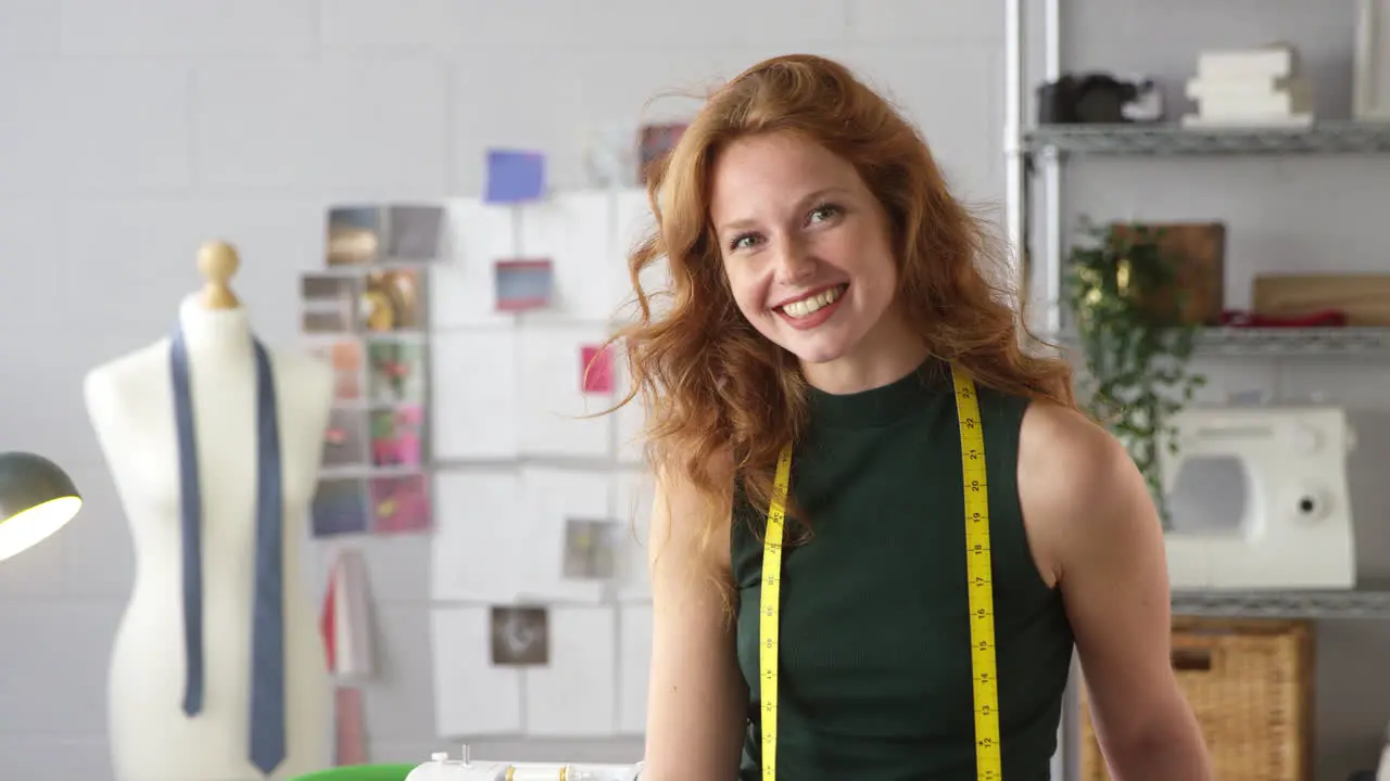 Portrait Of Female Student Or Business Owner With Tape Measure Working In Fashion Sitting On Desk