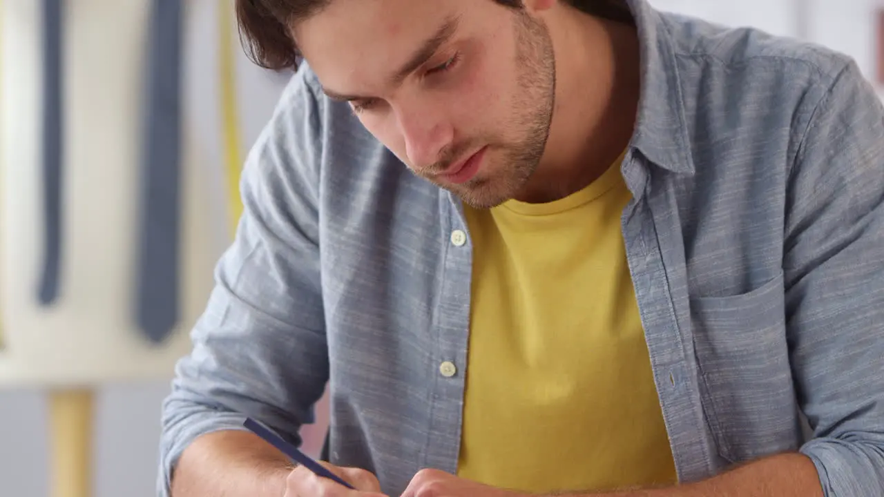 Male Clothes Designer Concentrating As He Works In Fashion Studio Sketching Designs