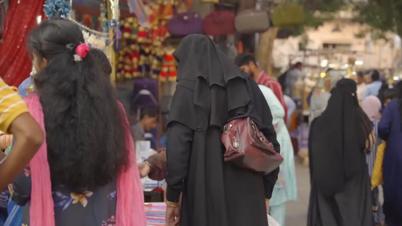 Indian women wearing traditional hijab burka and fully covered walking through the market outside Charminar for shopping slow motion shot