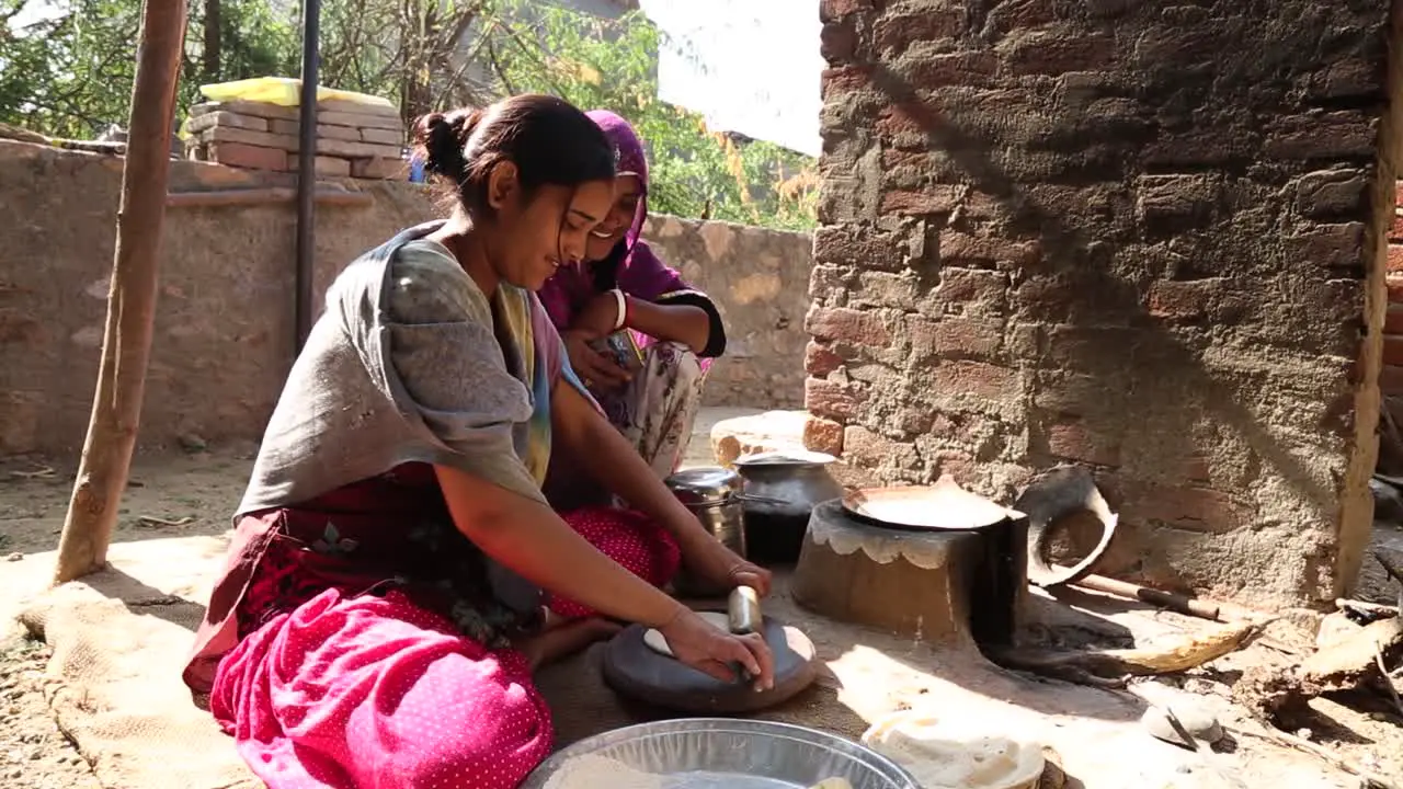 Domestic life of young Indian girls preparing traditional chapati bread with rolling pin Rajasthan