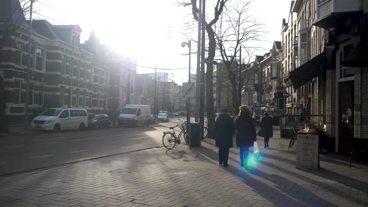 Two women pedestrians walking down a road with sun flare