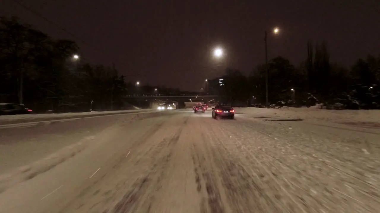 POV shot driving through downtown Helsinki with pedestrians walking across crossings at night