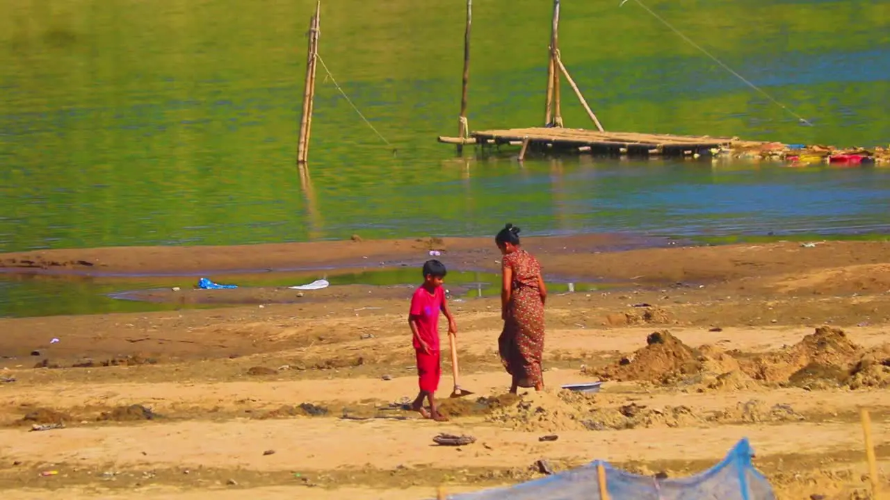 Mother and child working on Surma river bank for agriculture soil