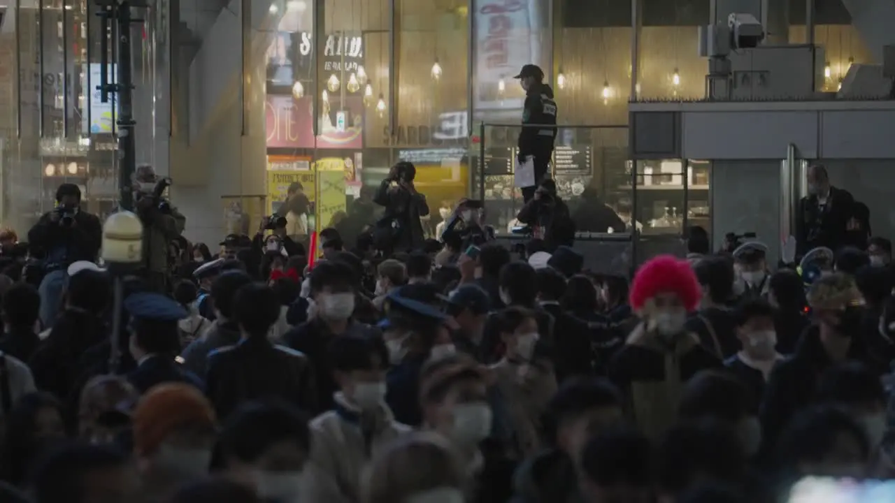 Photographers Taking Pictures Of The Crowd Scrambling At Shibuya Crossing On Halloween Night With Policemen On Guard static shot slow motion