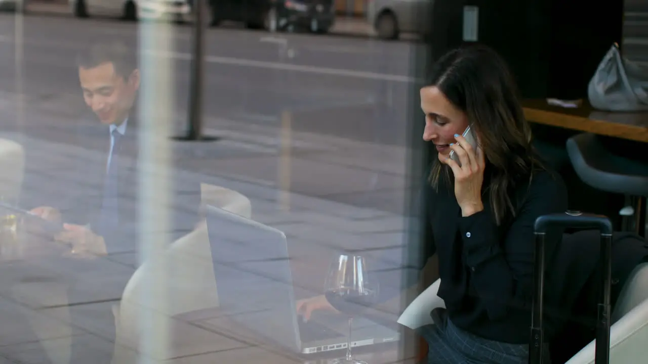 Side view of beautiful caucasian businesswoman talking on mobile phone and working on using laptop i