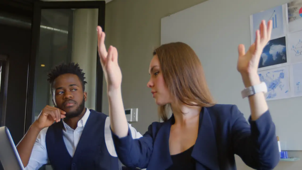 Side view of young mixed-race business team planning and sitting with laptop in a modern office 4k