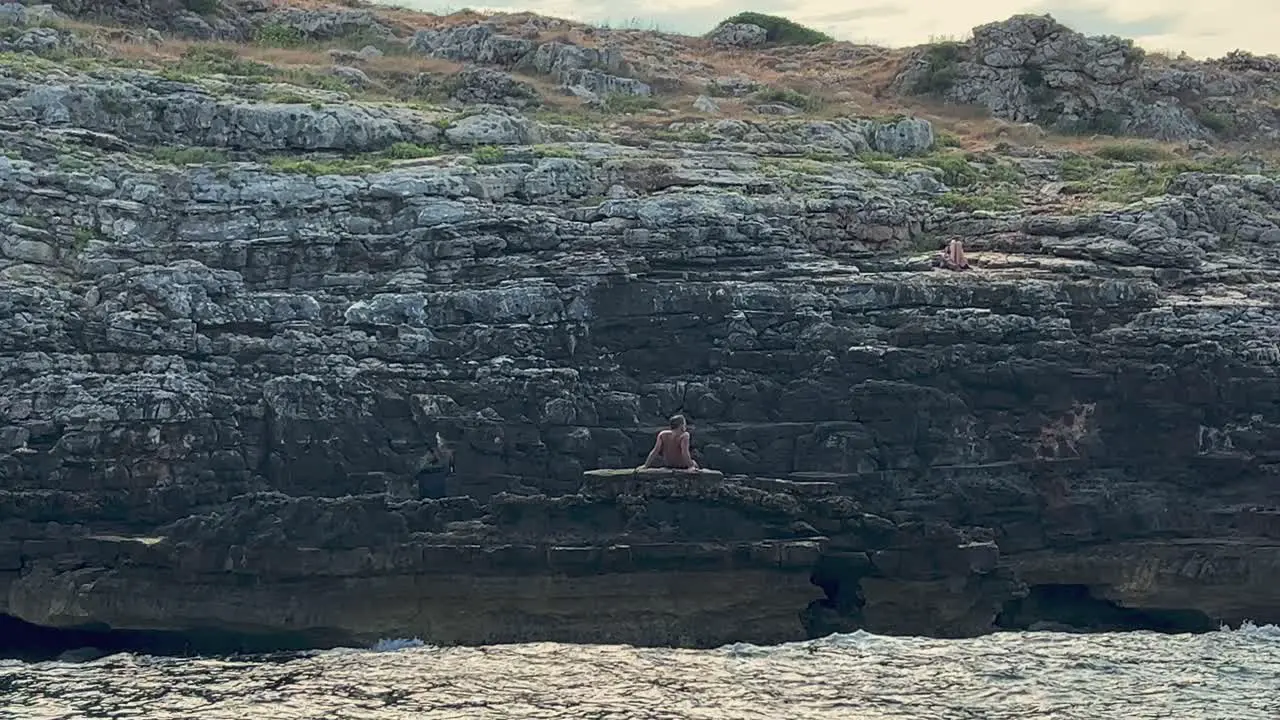 Man lying on rocks of Ionian coast of Salento in Apulia gets tan