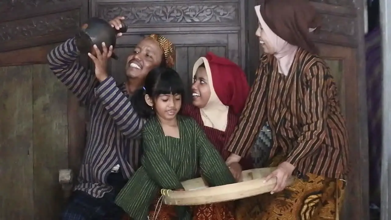 A happy Javanese family couple with their two children with an earthen jug Central Java Indonesia