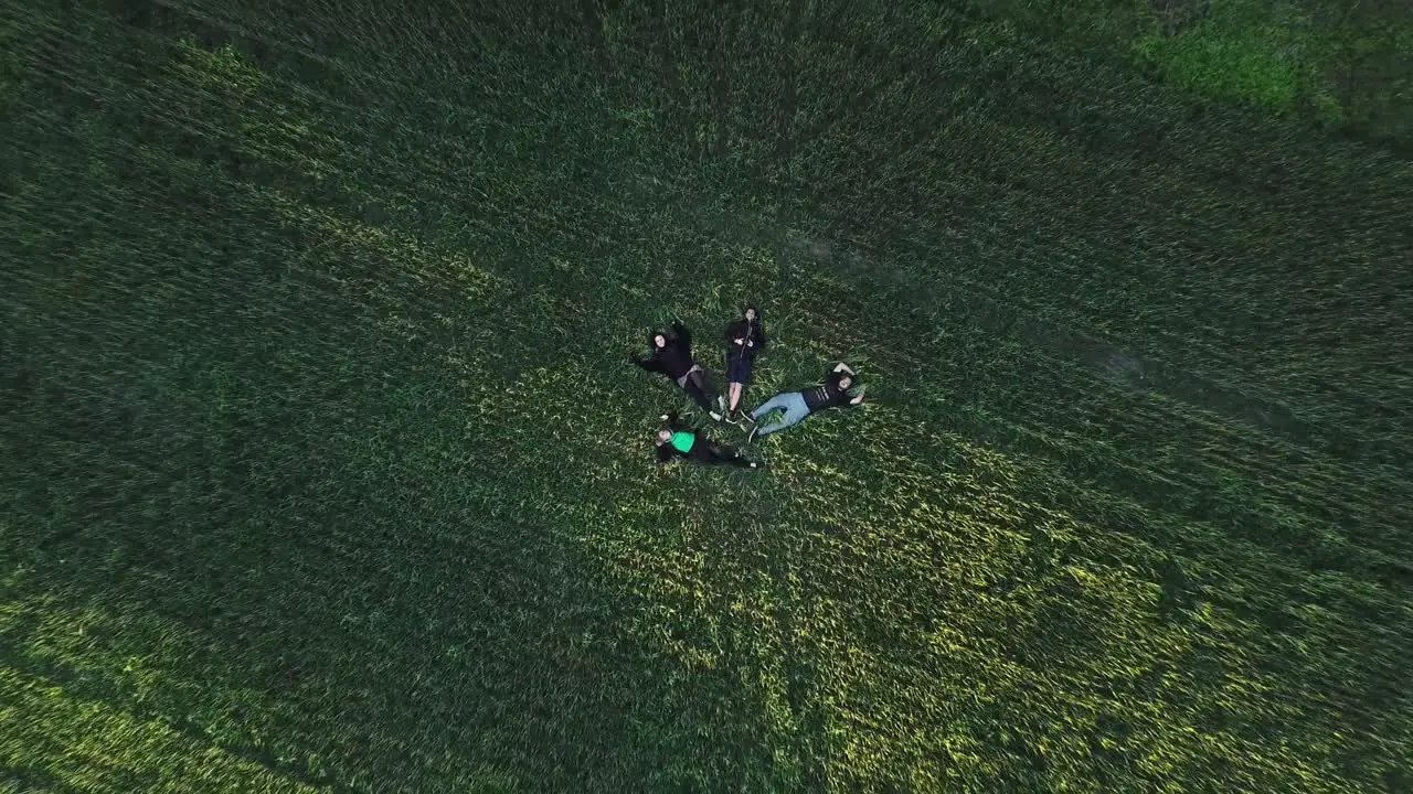 Group Of Friends Lying On The Grassy Ground Near Windmill top-down drone shot