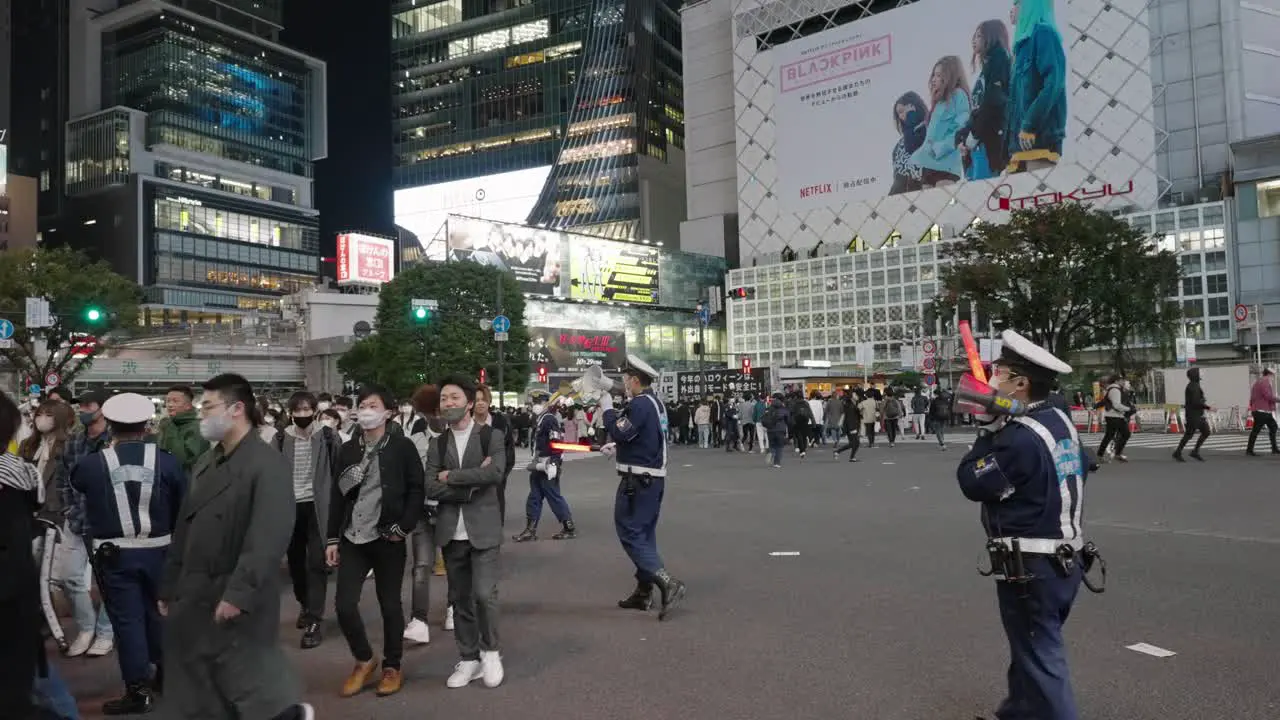 Police Officers With Megaphone And LED Traffic Baton Directing Crowds At The Shibuya Crossing On Halloween Night In Tokyo Japan