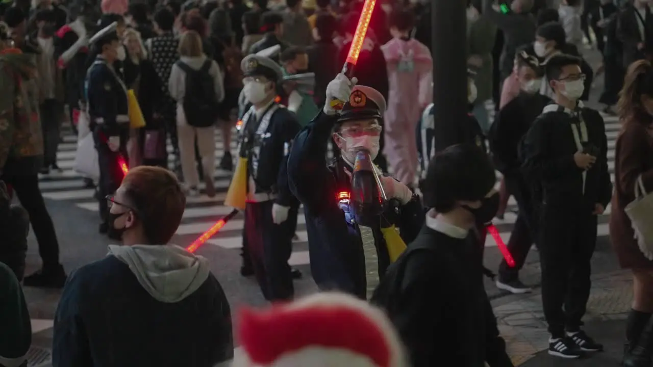 Shibuya Halloween Cops Wearing Face Mask Controlling The Crowd With LED Baton And Megaphone On Halloween Night At The Shibuya Crossing In Tokyo Japan