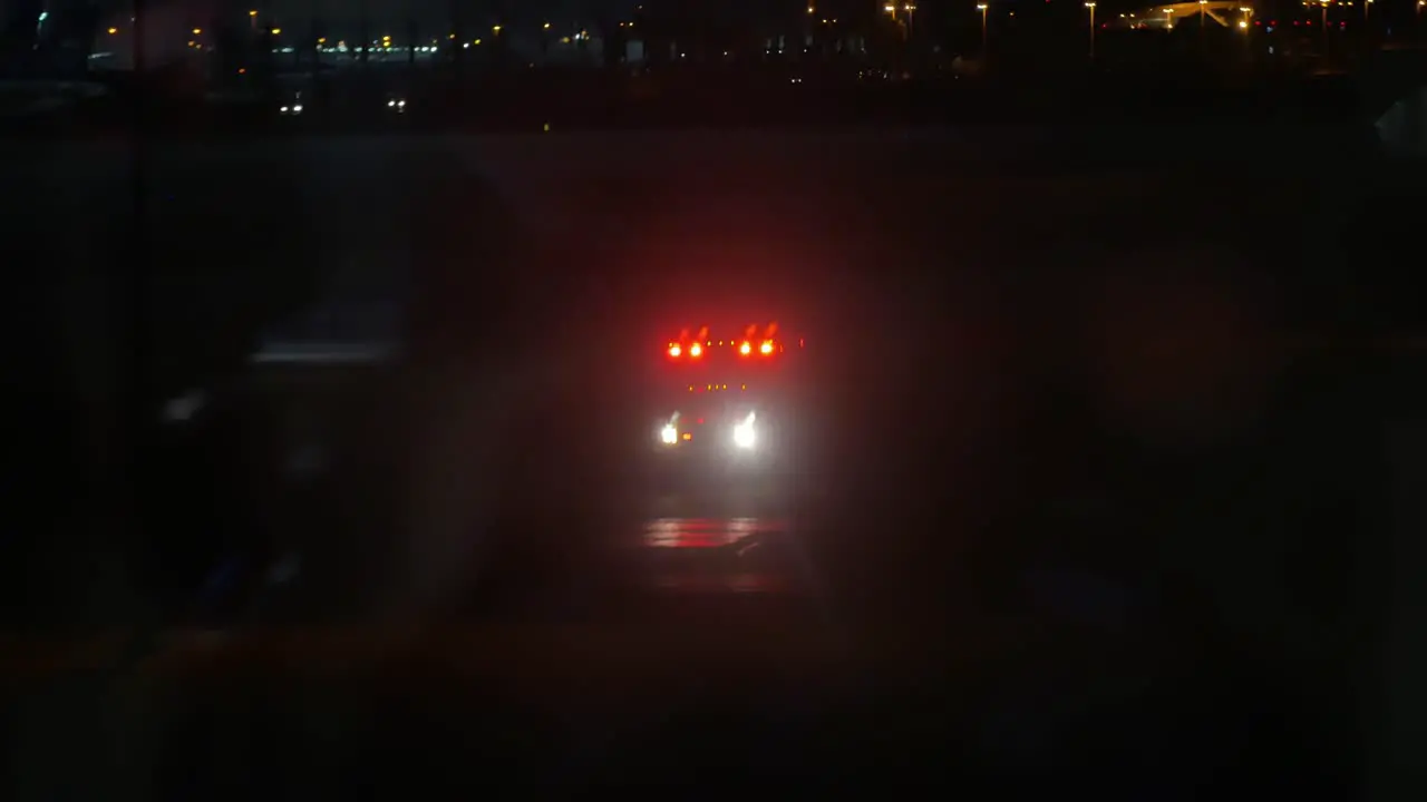 A shot of an ambulance going down the airport runway at night