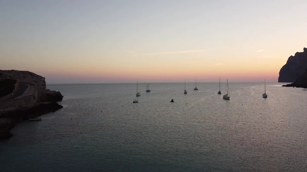 sunrise on the coast with sailboats in the sea