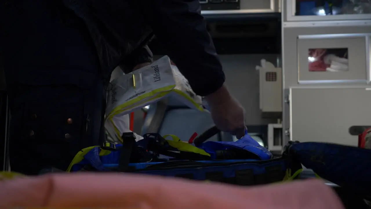 Emergency medical technician prepares medic gear on a gurney inside an ambulance to be ready for emergency response