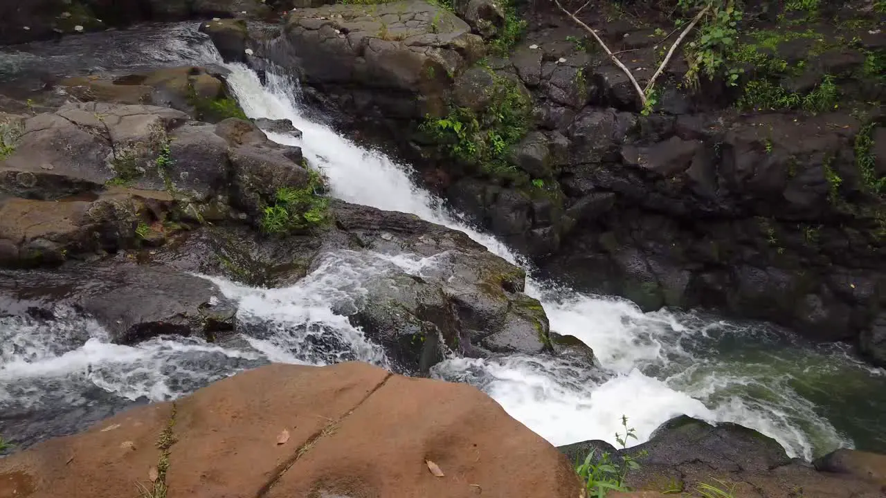 4K Hawaii Kauai boom up from large rocks to a split waterfall joining together below