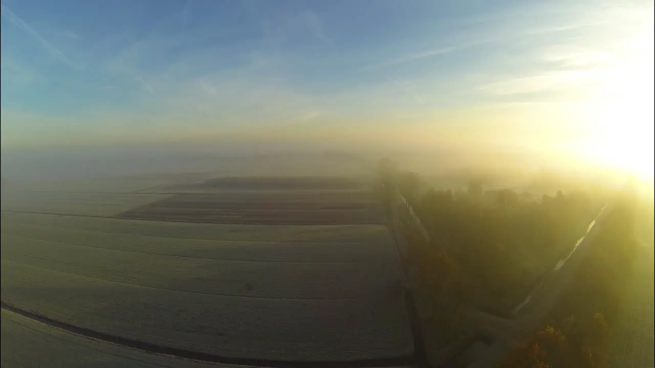 Aerial of sunrise through fog above a frozen landscape