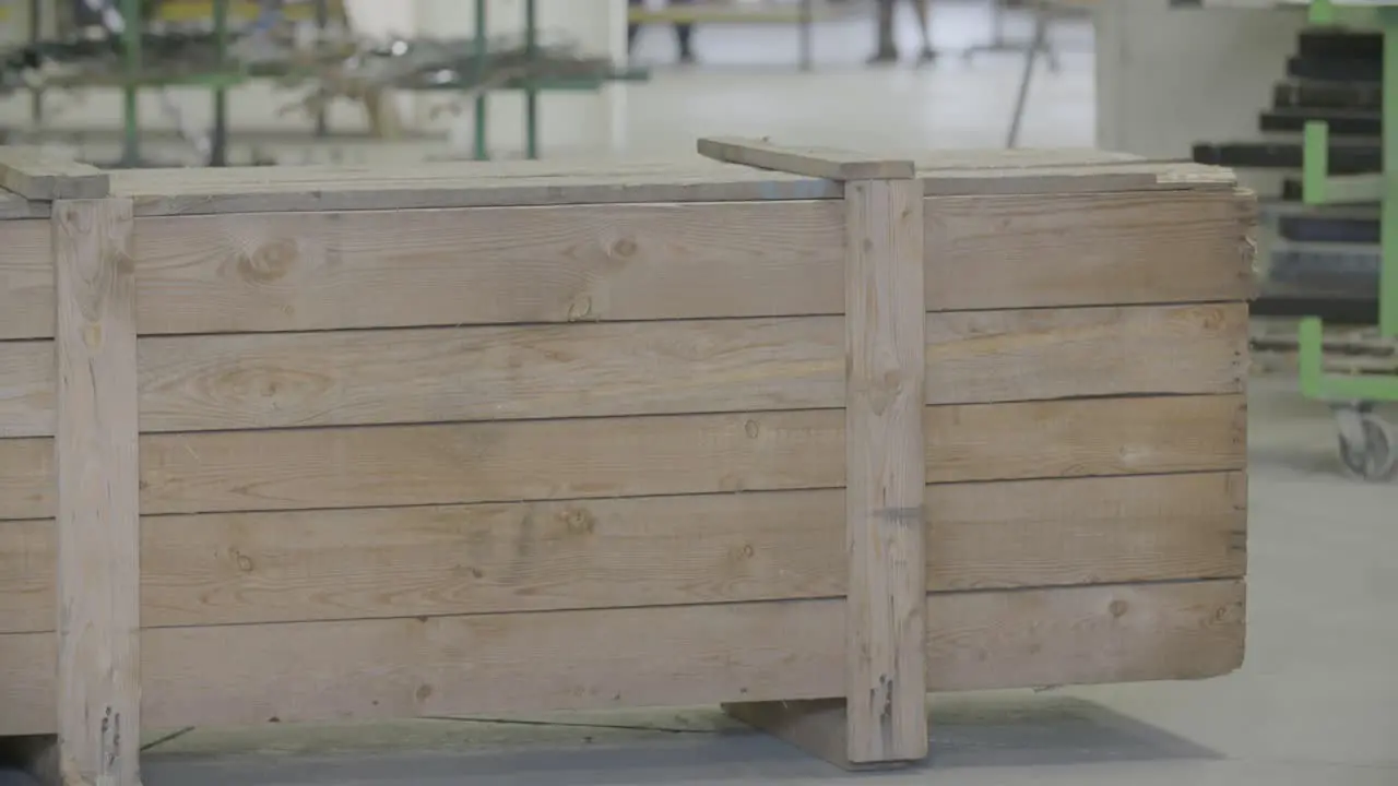 Handheld footage of a forklift placing a large wooden box in an industrial setting everything in focus