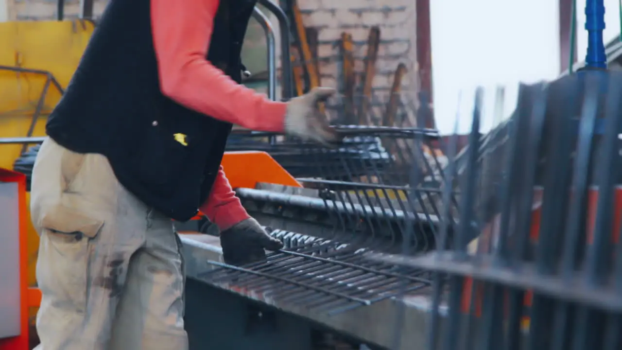 Factory worker bending grid from steel bars Workman bends metal at factory