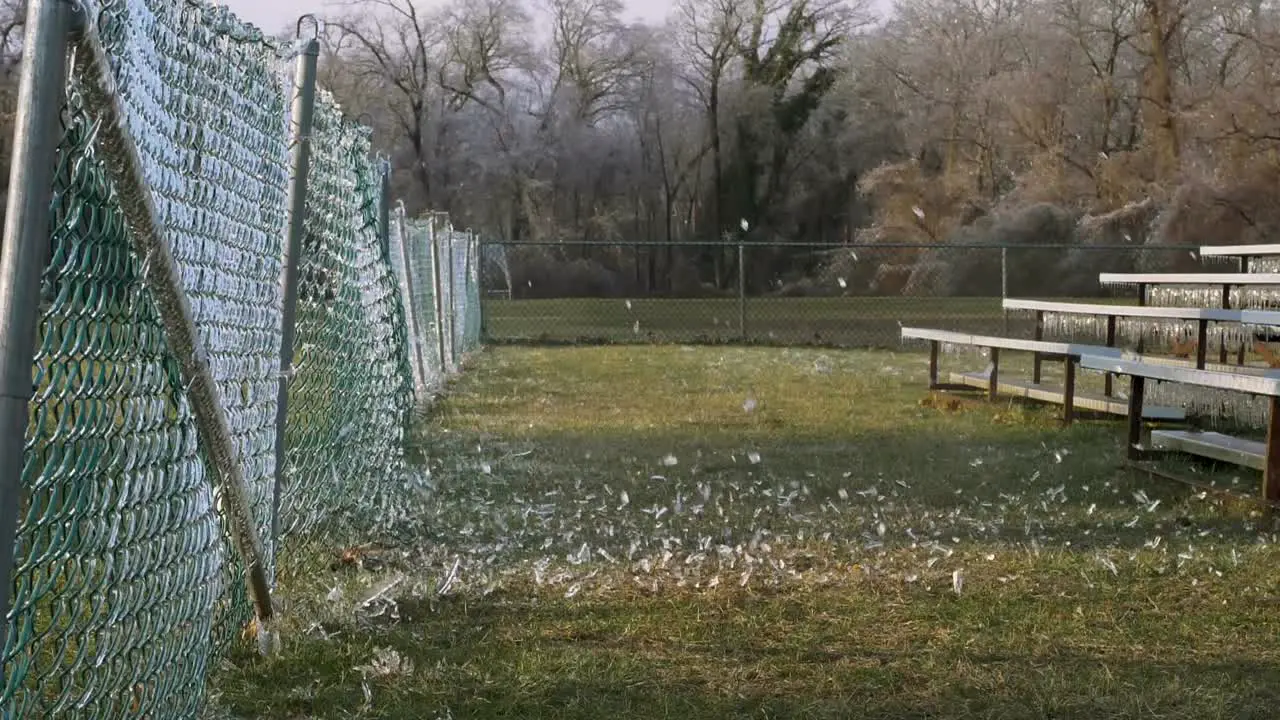 SLOW MOTION A side shot of a soccer ball slamming into an icy fence which explodes the shattered ice into the air