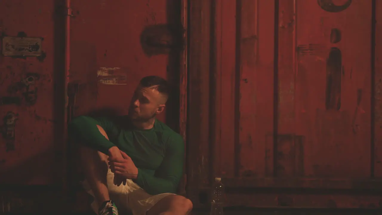 Male Boxer Rests Sitting Next To The Punching Bag