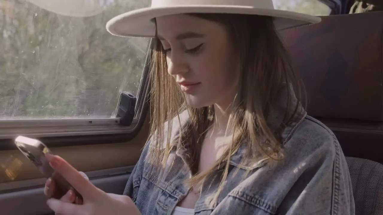 A Beautiful Young Woman Typing On Her Cell Phone While Smiling During A Roadtrip In The Caravan