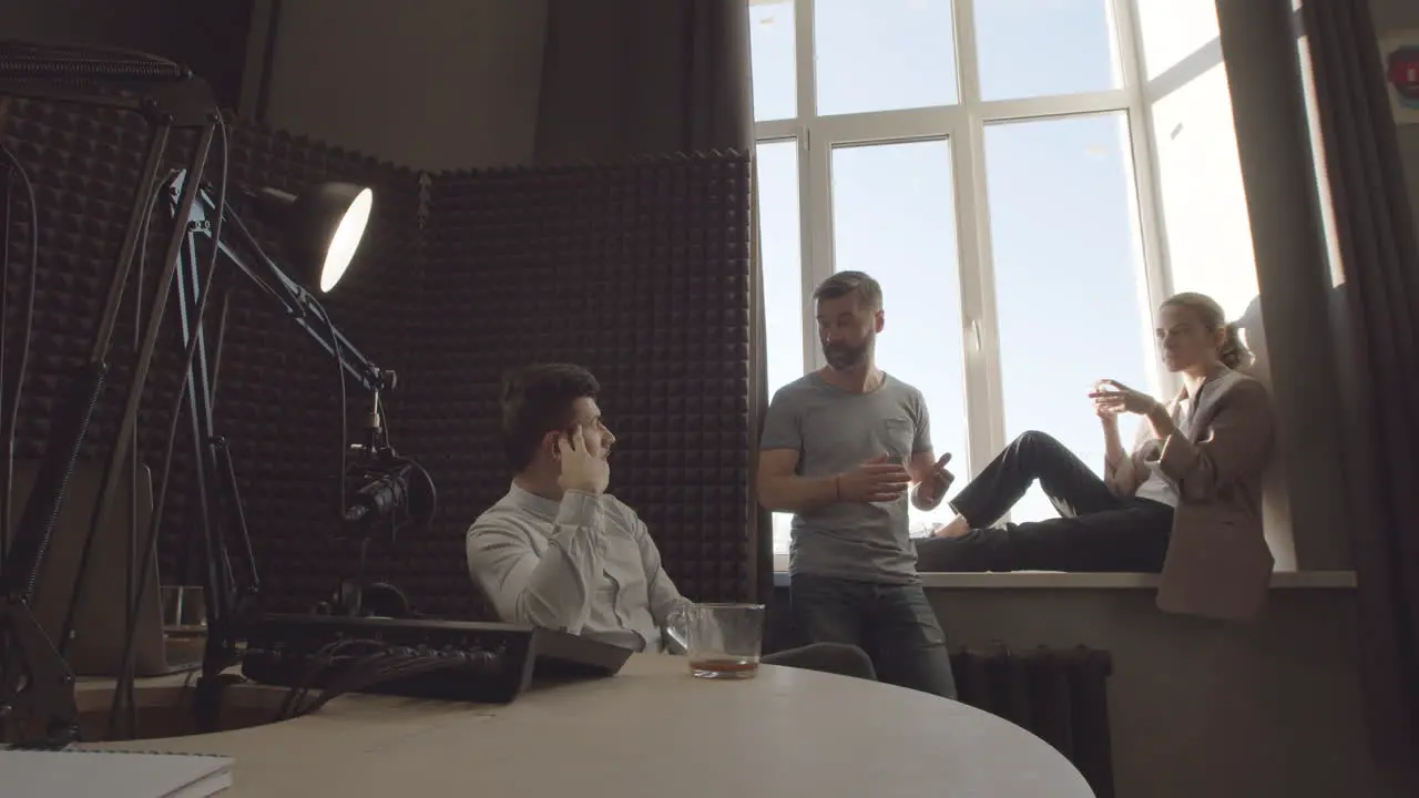 Bearded Radio Professional Talking With His Two Stylish Program Guests Before Or After Recording In A Radio Studio