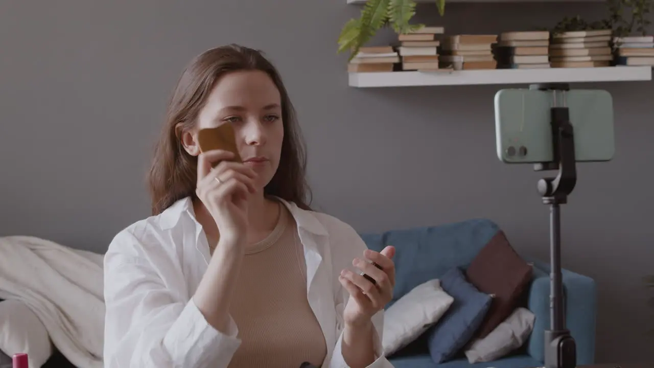 Young Cute Vlogger Woman Explaining To The Camera How To Use A Wooden Gua Sha On Her Face