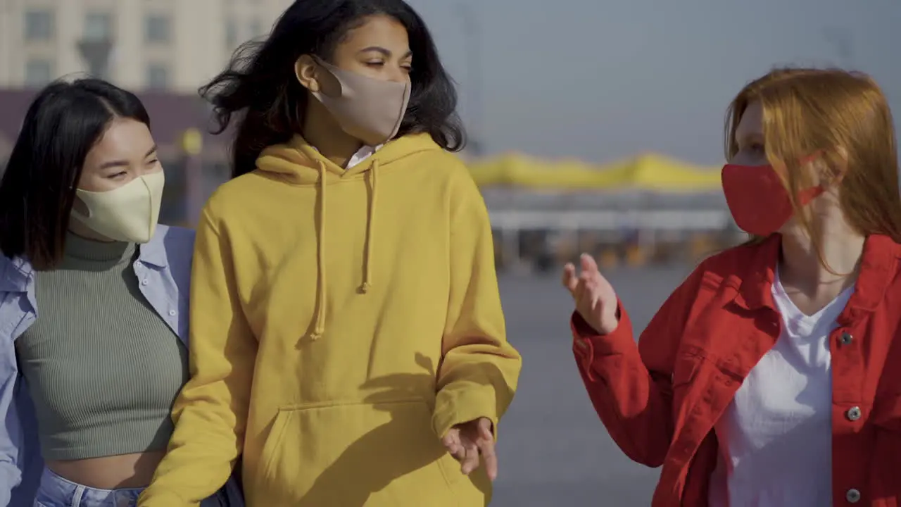 Multi Ethnic Female Friends Walk And Talk Together With Face Mask Outdoors