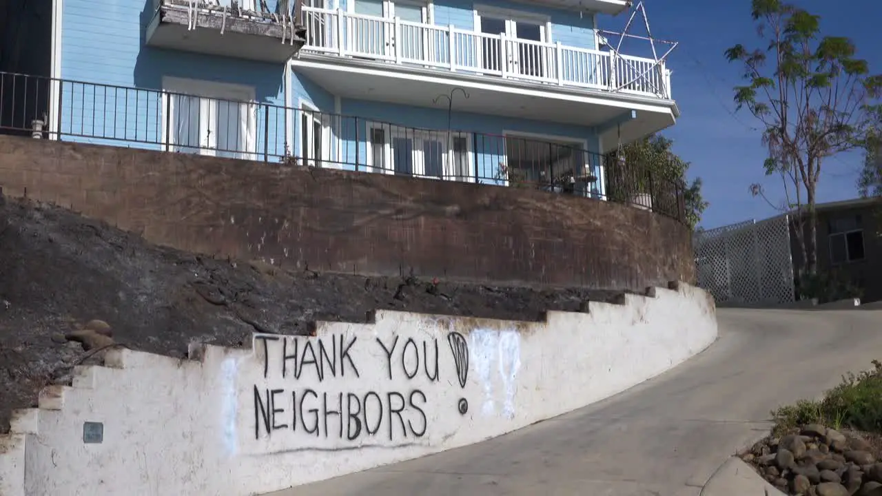 A thank you to neighbors is spray painted on a wall outside a house during the devastating Thomas Fire in Ventura California