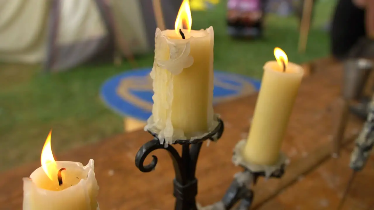 Three old burning candles on black candlesticks placed on wooden table slow motion shot