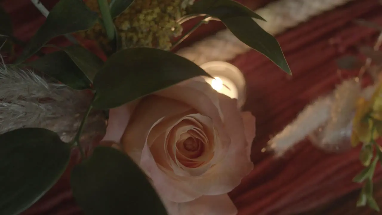 Top-down shot of a light pink rose and a tiny tea candle on a wedding reception table