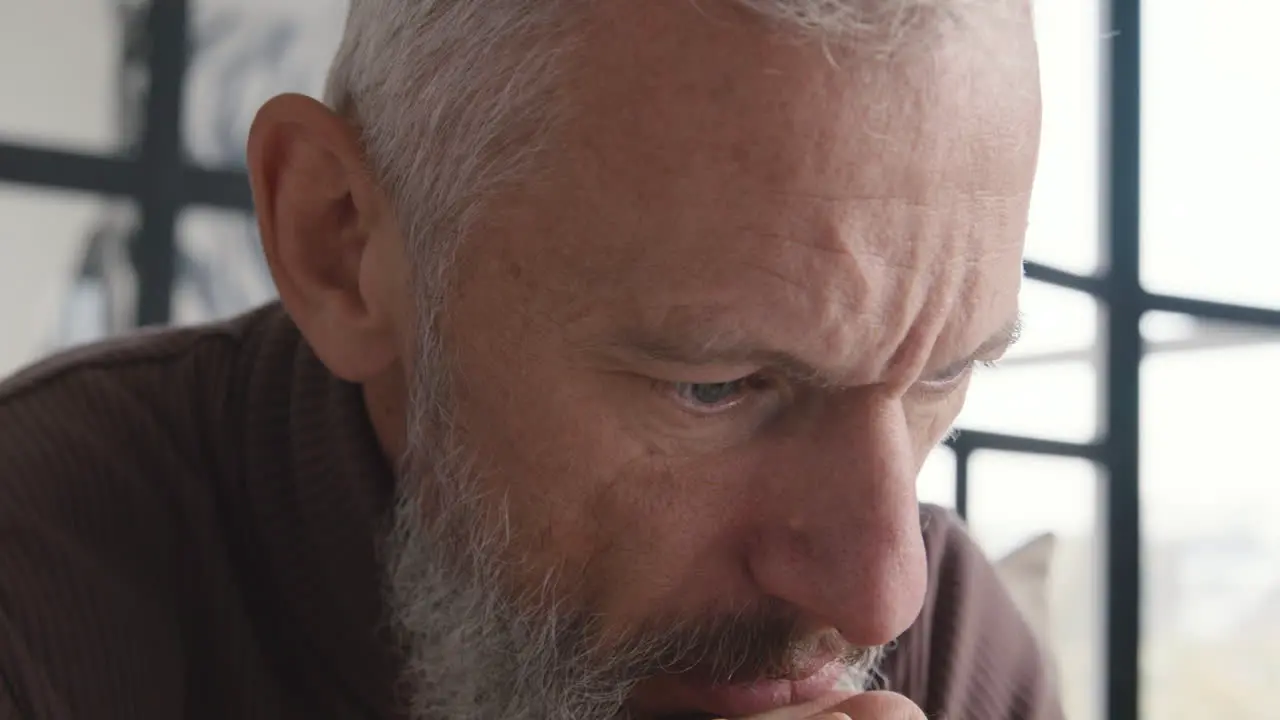 Close Up Of An Upset Middle Aged Man Worrying And Thinking About Something While Sitting On Sofa At Home