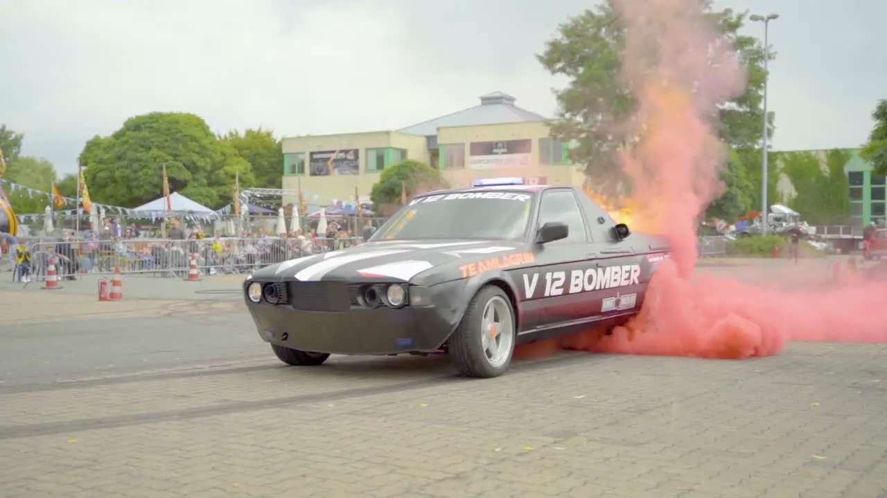 Dragster Car Burning Out Rear Tires With Red Smoke And Flame During A Car Stunt Show