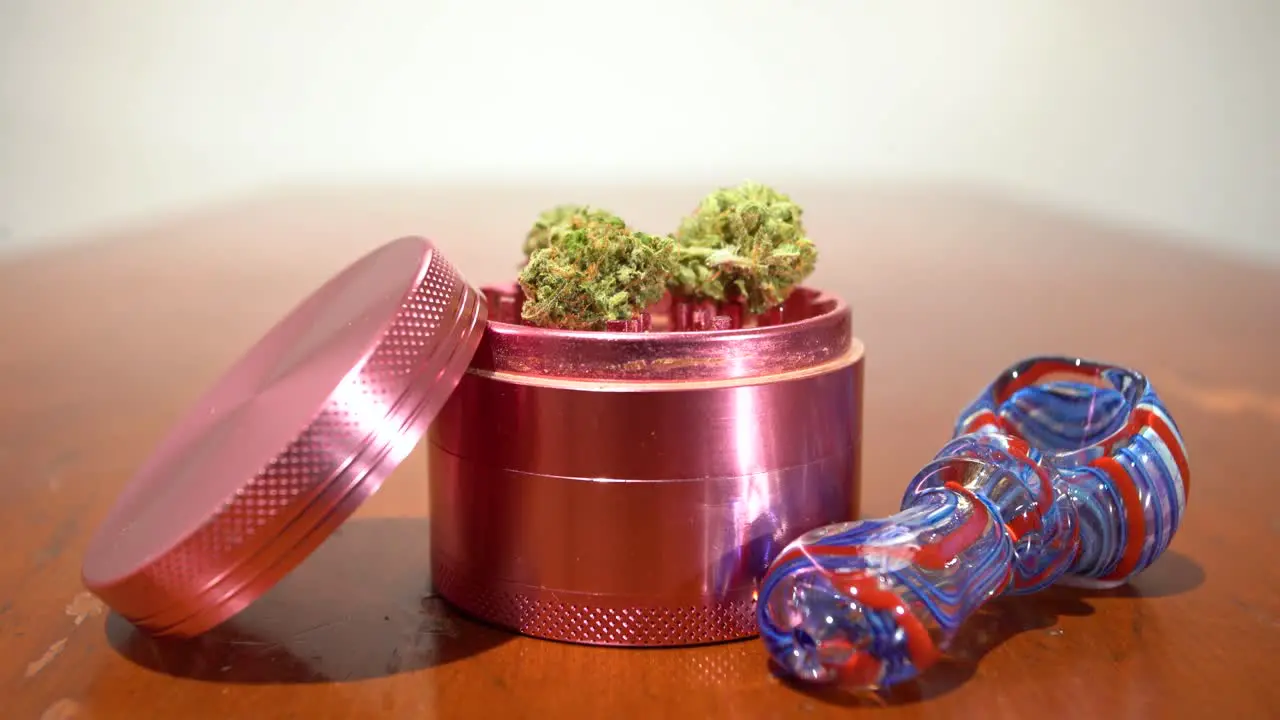 Tilt down to pipe next to grinder with cannabis in it