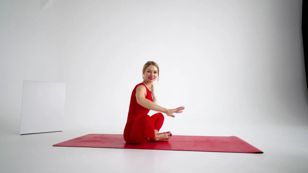 Beautiful young woman wearing red sportswear doing yoga or pilates exercise pose on white background