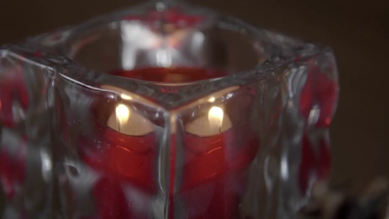 Close-up of small red tea light flame flickers in a glass holder