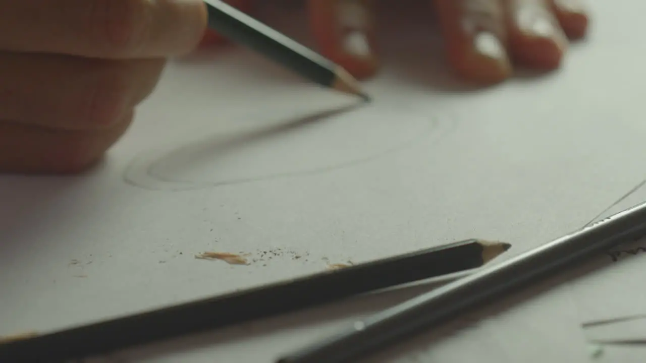 A person draws a circle on a piece of paper with a pencil