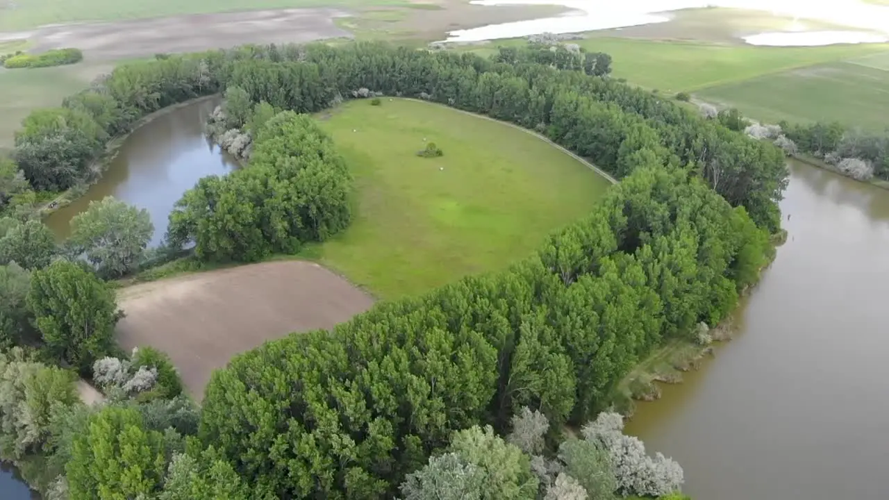 Aerial drone shot of a backwater river bend with a green field in the middle