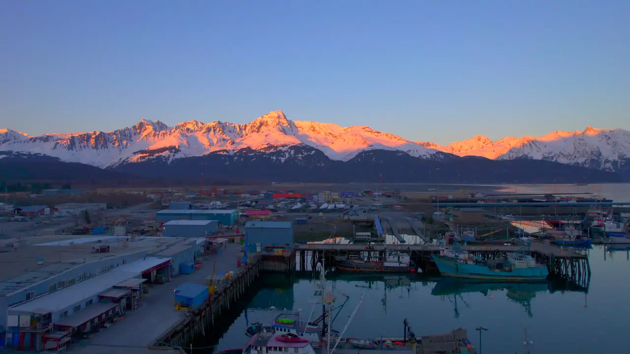 Drone flying up over Seward Boat Harbor towards the mountains at sunset in Seward Alaska