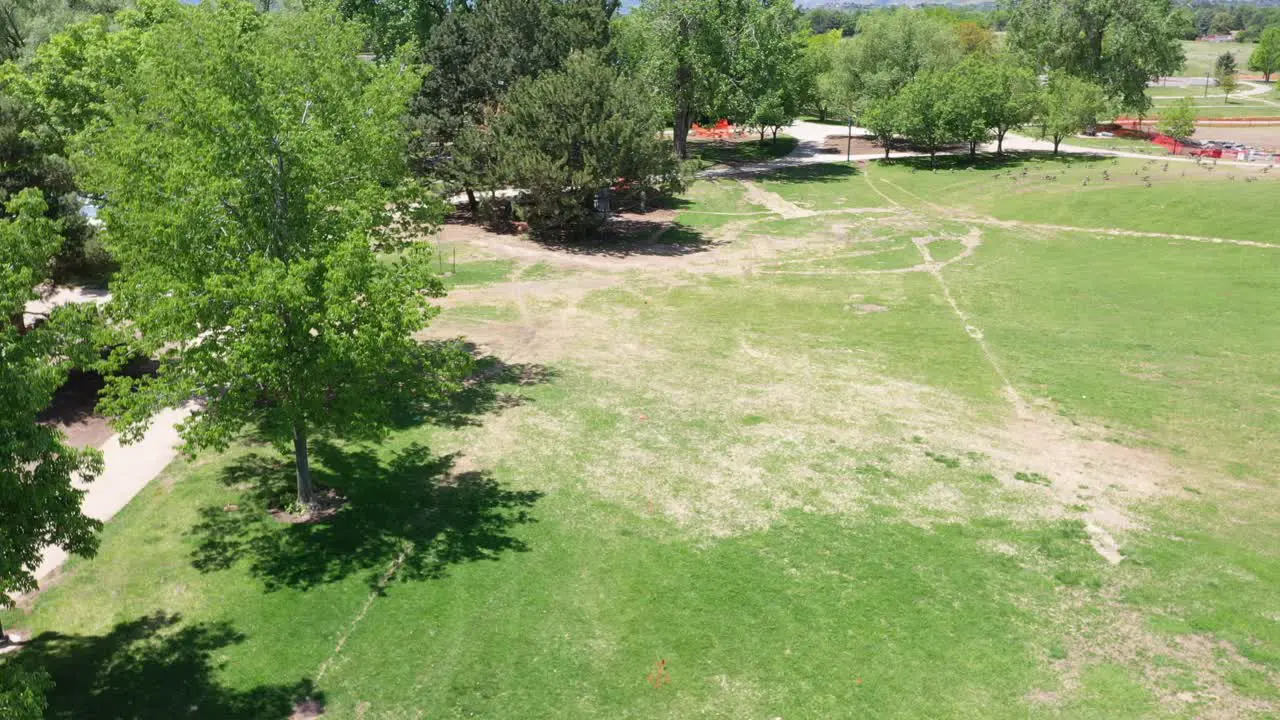 A rising drone shot of a flag marker placed on the lawn of a public park