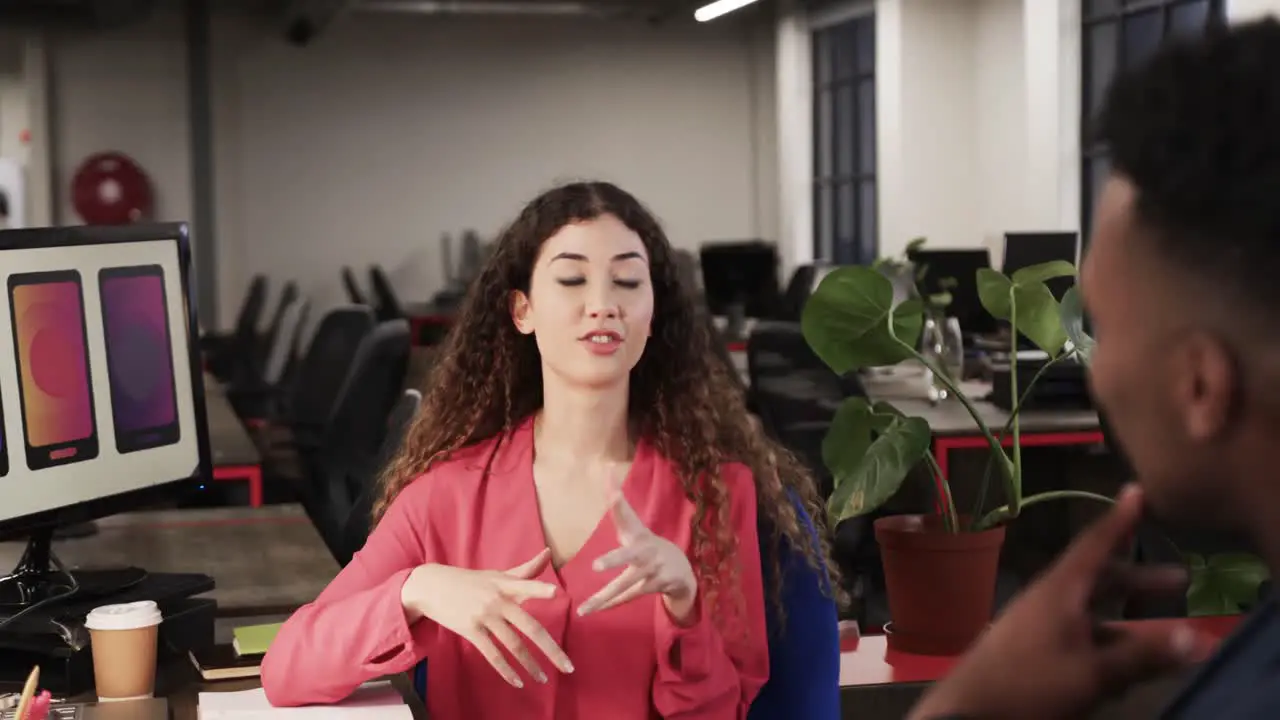 Two happy diverse creative colleagues in discussion at computer in casual office slow motion