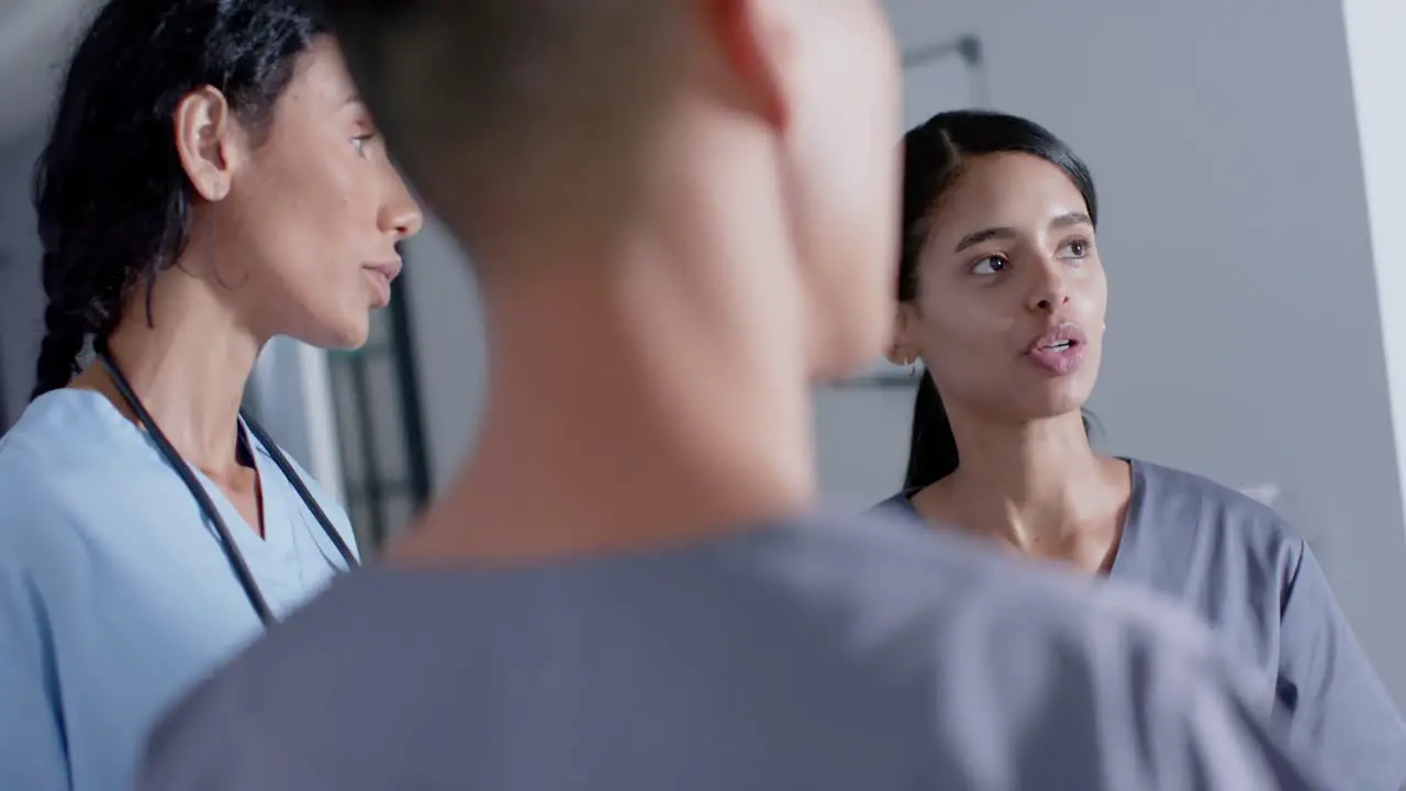 Diverse doctors and nurses talking in corridor at hospital in slow motion