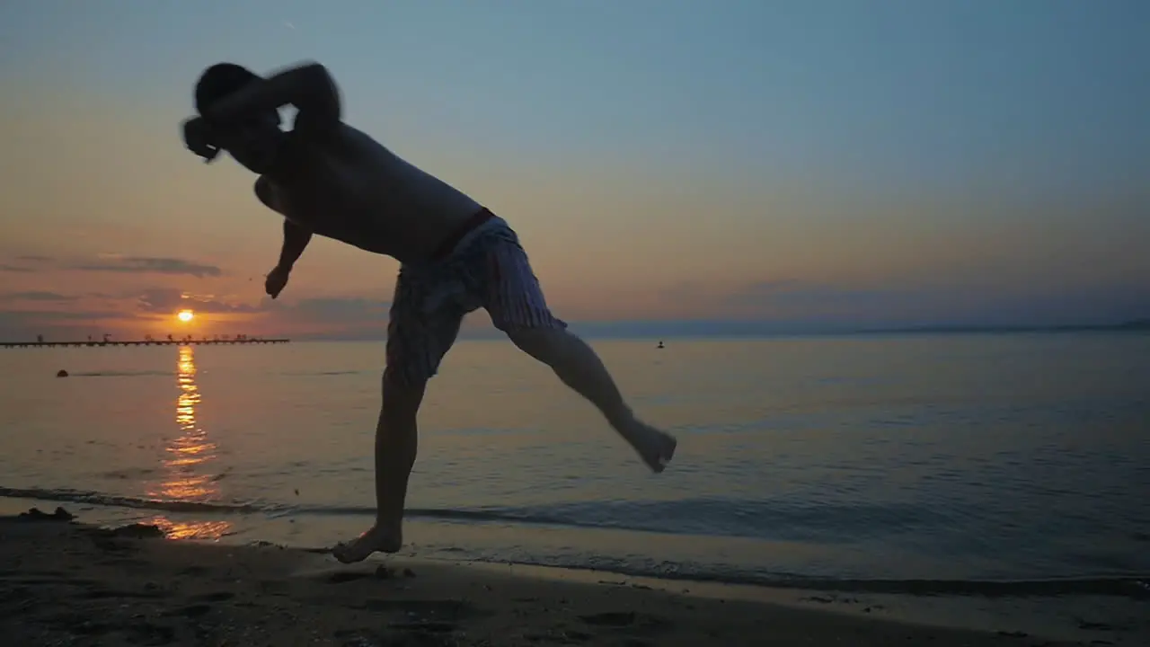 A guy doing acrobatic tricks on the beach