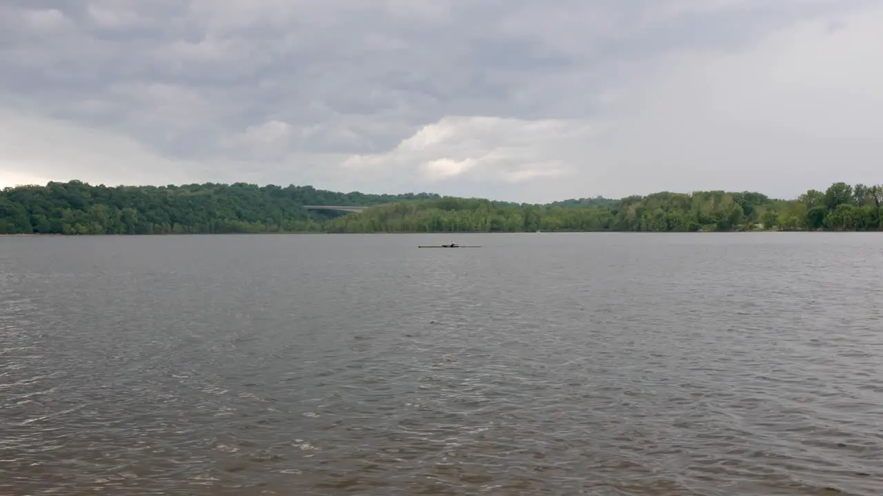 A single rower moves across this midwestern urban lake with storm clouds in the background