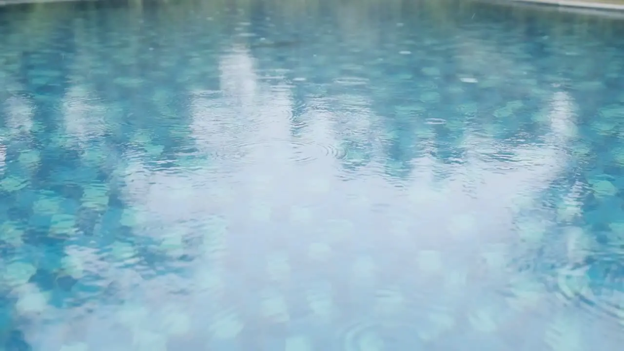 Raindrops falling on the surface of a swimming pool slow motion