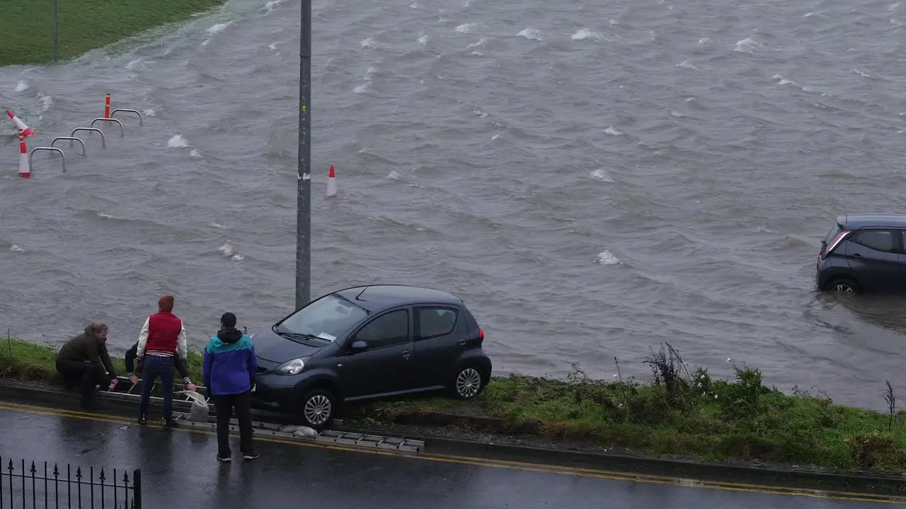 Group of residents manage to push car out of flooded carpark