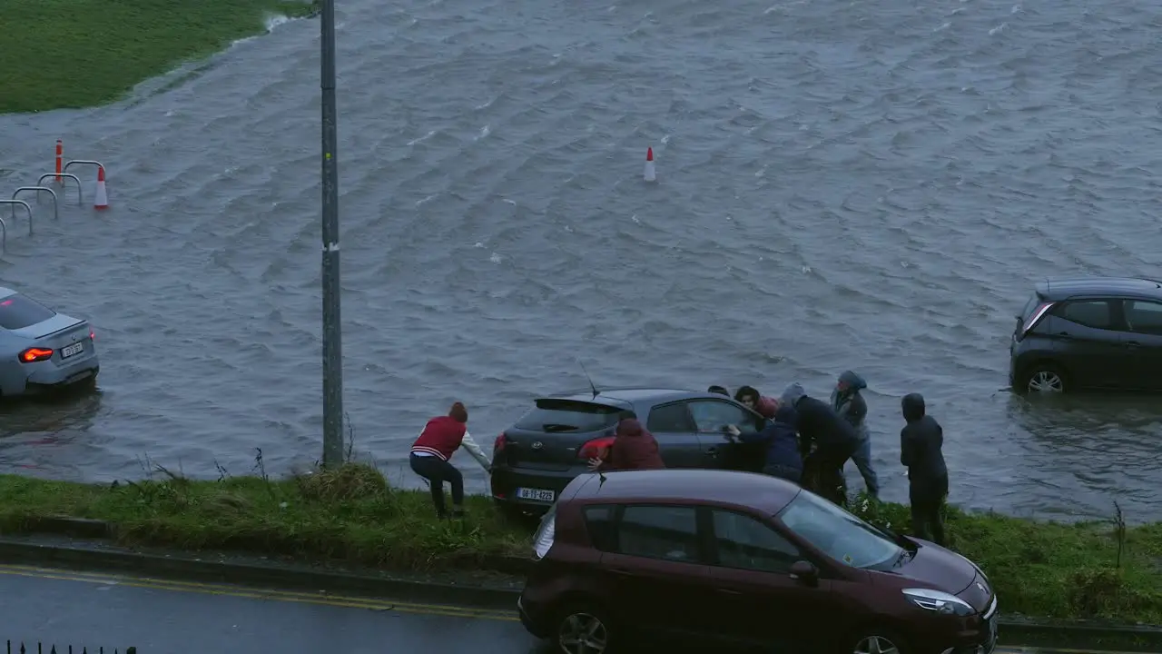 Residents come together Pushing car out of flooded parking during storm