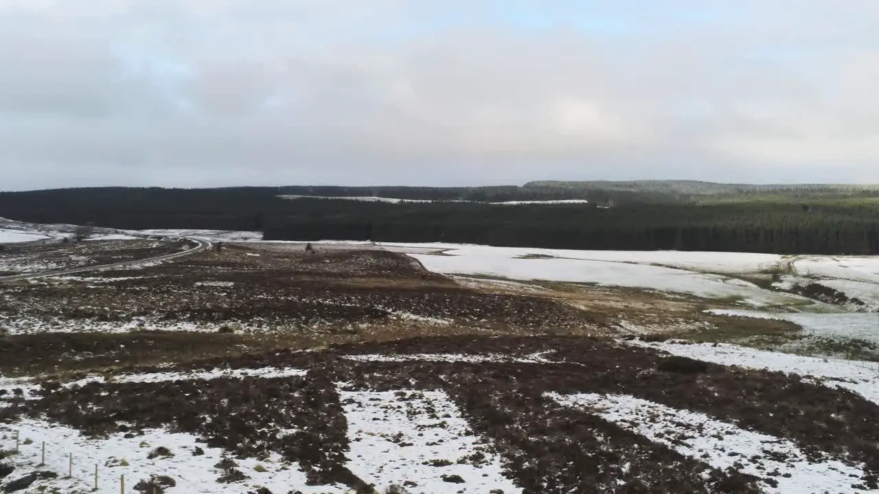 Snowy rural winter valley countryside aerial agricultural moorland landscape pan right