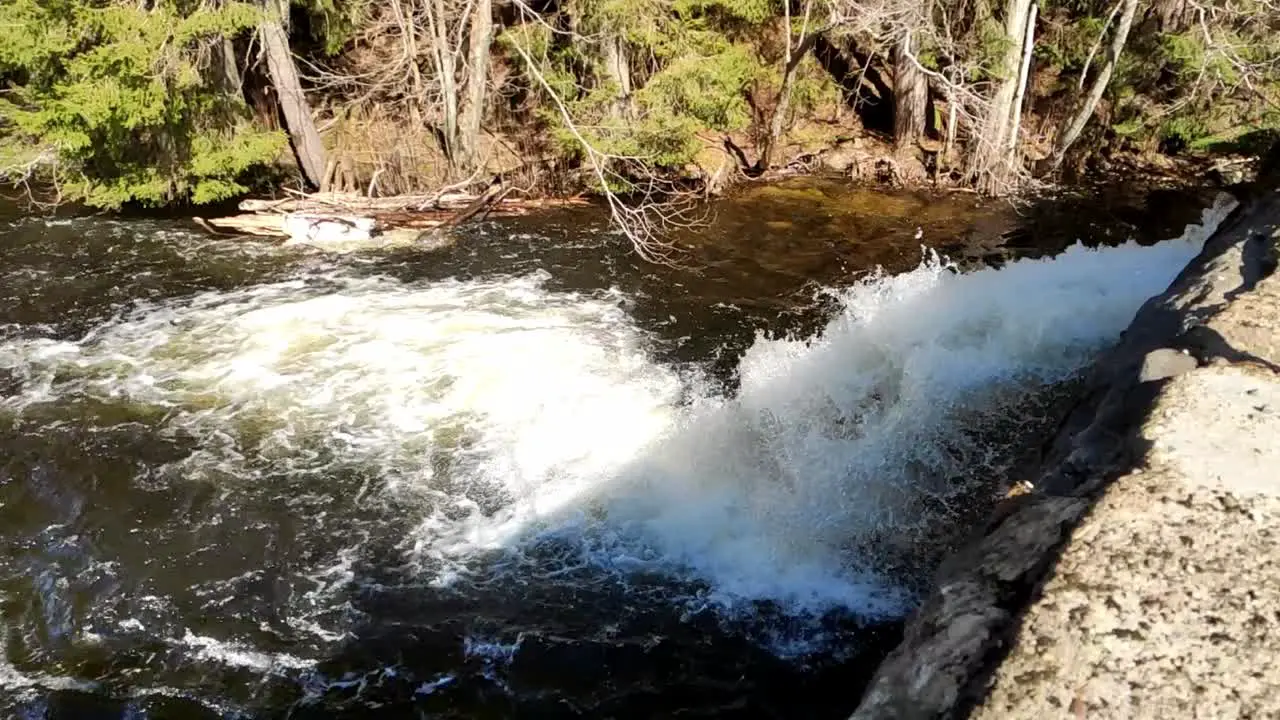 Handheld clip of water flowing down the dam in slow motion on a sunny day