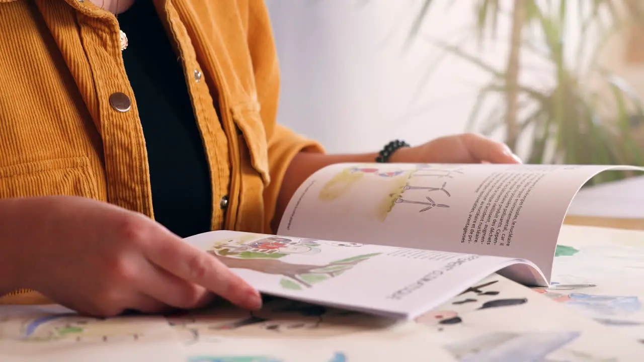 Girl flipping through children's book on desk at home